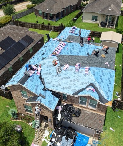 Aerial view of a Hill Heights crew installing synthetic underlayment across a large roof