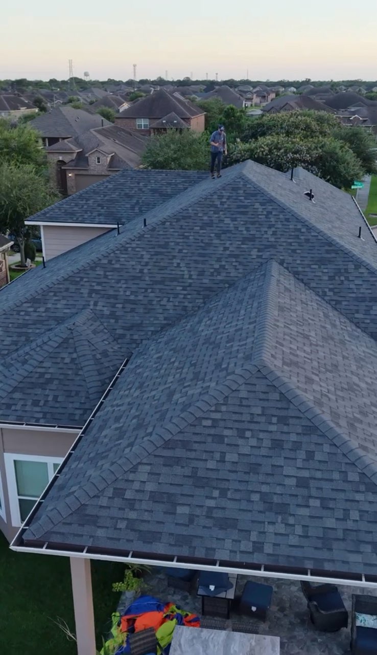 Finished charcoal shingle roof photographed from the air at sunset over a Texas neighborhood